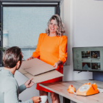 Twee collega's van Pack Company aan een bureau.