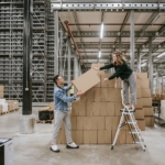 Jan en Heleen van Pack Company geven elkaar een kartonnen doos aan.